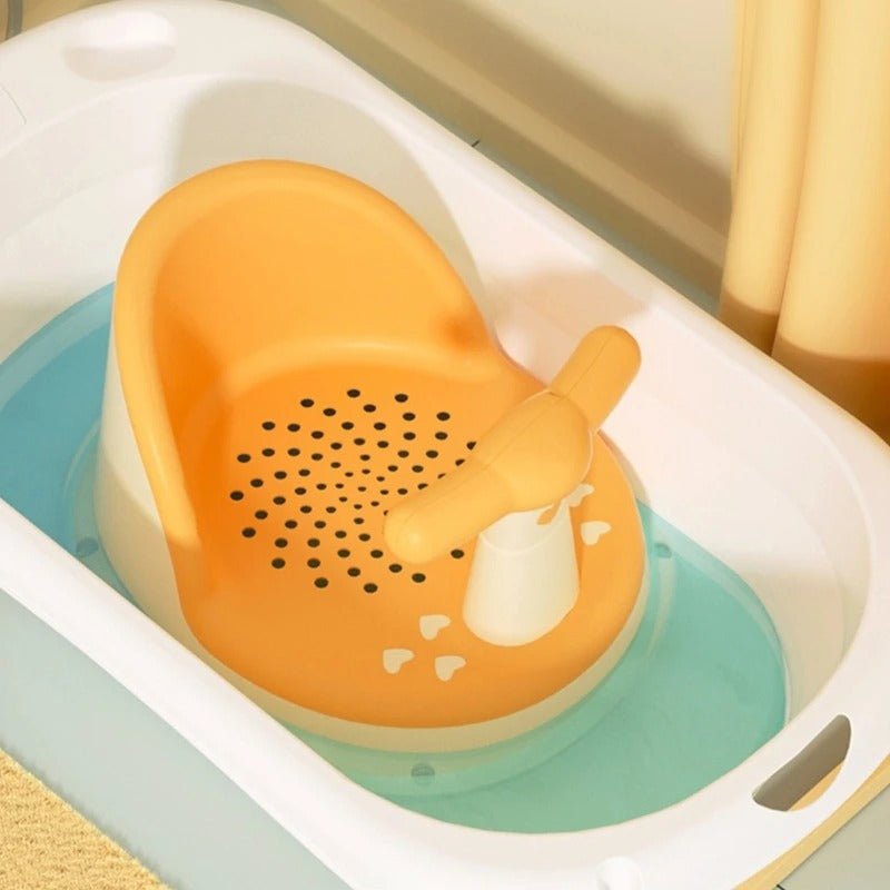 Siège de bain bébé antidérapant en plastique orange avec motifs perforés, installé dans une baignoire avec eau.