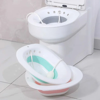 Baignoire pliable et portable RelaxFold rose et blanche posée au sol à côté des toilettes.