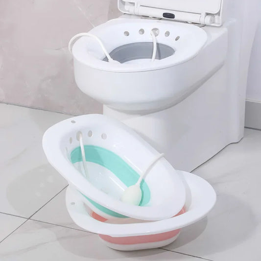 Baignoire pliable et portable RelaxFold rose et blanche posée au sol à côté des toilettes.