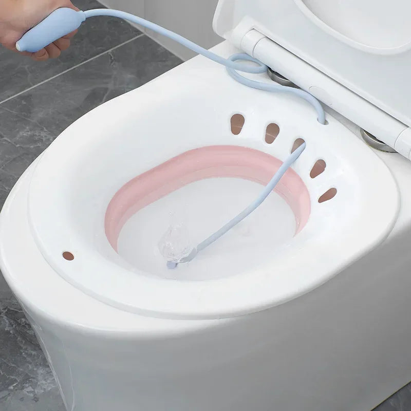 Bain de siège pliable rose et blanc pour toilettes avec pompe manuelle pour femme enceinte et post-partum.