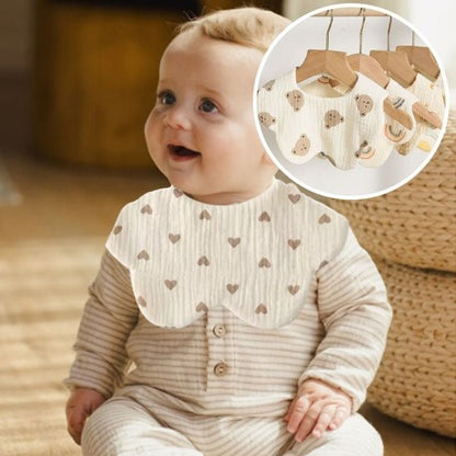 Le bébé souriant porte son bavoir et regarde autour de lui.