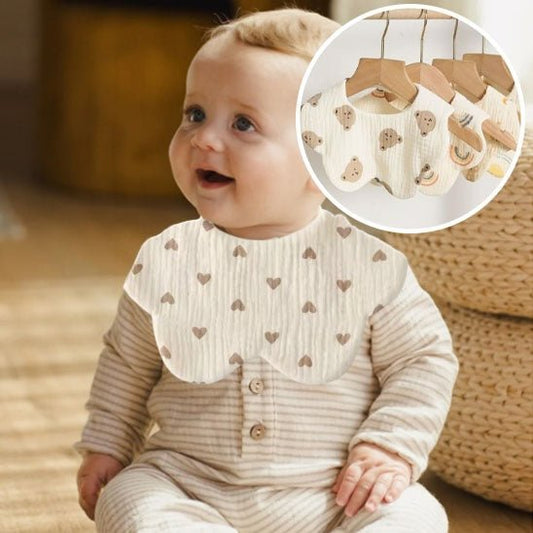 Le bébé souriant porte son bavoir et regarde autour de lui.