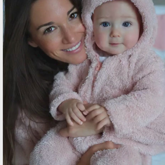 Enjoué aux côtés de sa maman, qui est habillée d'une cape de bain bébé.